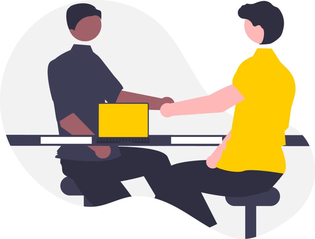 Two-people-shaking-hands-across-desk-with-laptop-between-them.