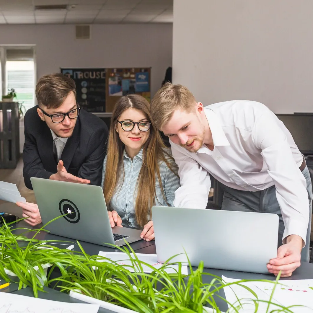 Content creation team collaborating on editorial SEO strategy using laptops in modern office workspace