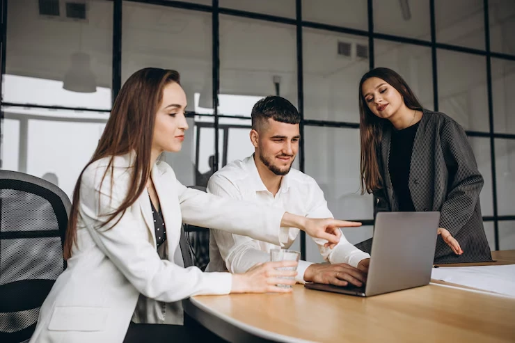 Three professionals collaborating on search engine image optimization strategy around laptop in modern office