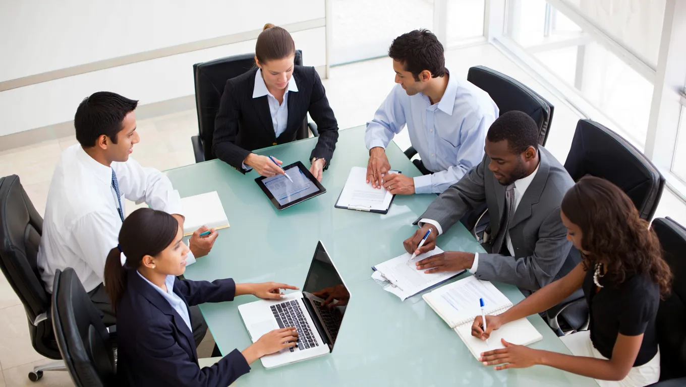 Professional outreach team strategizing guest post pitching campaigns around conference table with digital tools