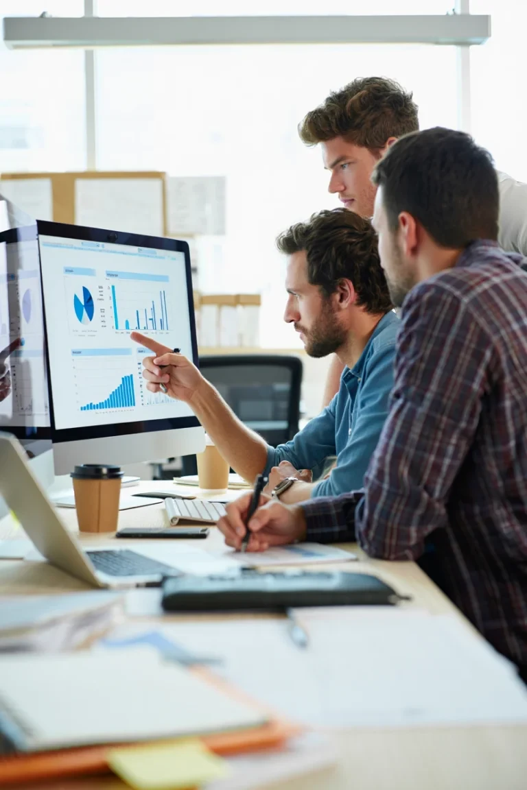 Three colleagues analyzing charts on monitor