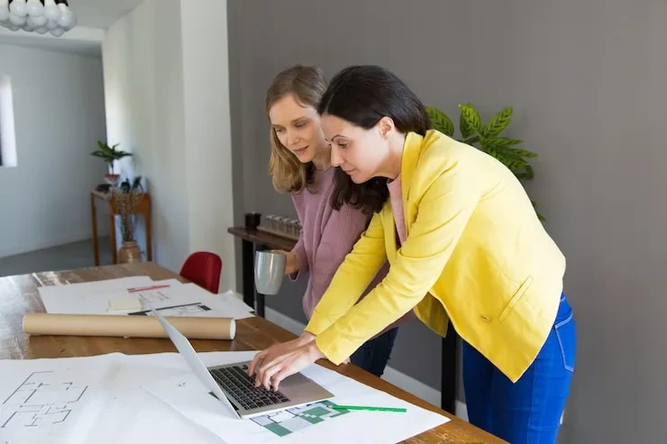 Two professionals reviewing data on laptop